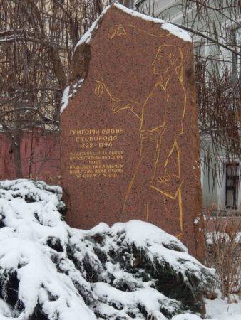 Пам'ятний знак Григорію Сковороді з барельєфом і золотим написом узимку під снігом