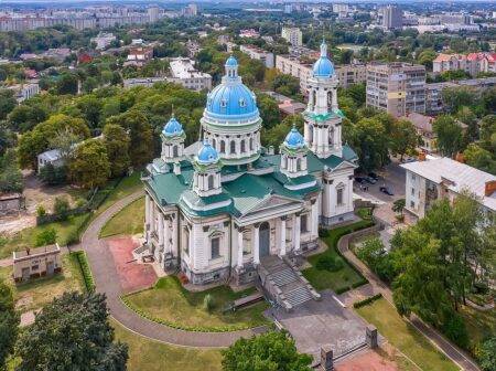 Панорамний вигляд на Свято-Троїцький собор у Сумах із блакитними куполами та зеленою покрівлею в оточенні міського пейзажу.